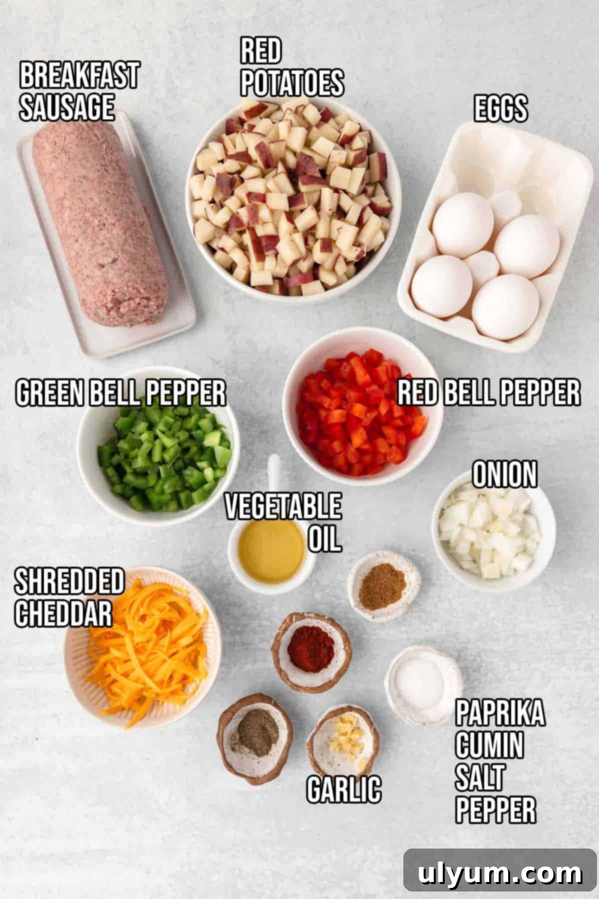 Breakfast sausage potato hash ingredients: breakfast sausage, diced red potatoes, diced green and red bell peppers, eggs, vegetable oil, onion, shredded cheddar, garlic, paprika, cumin, salt, and pepper.