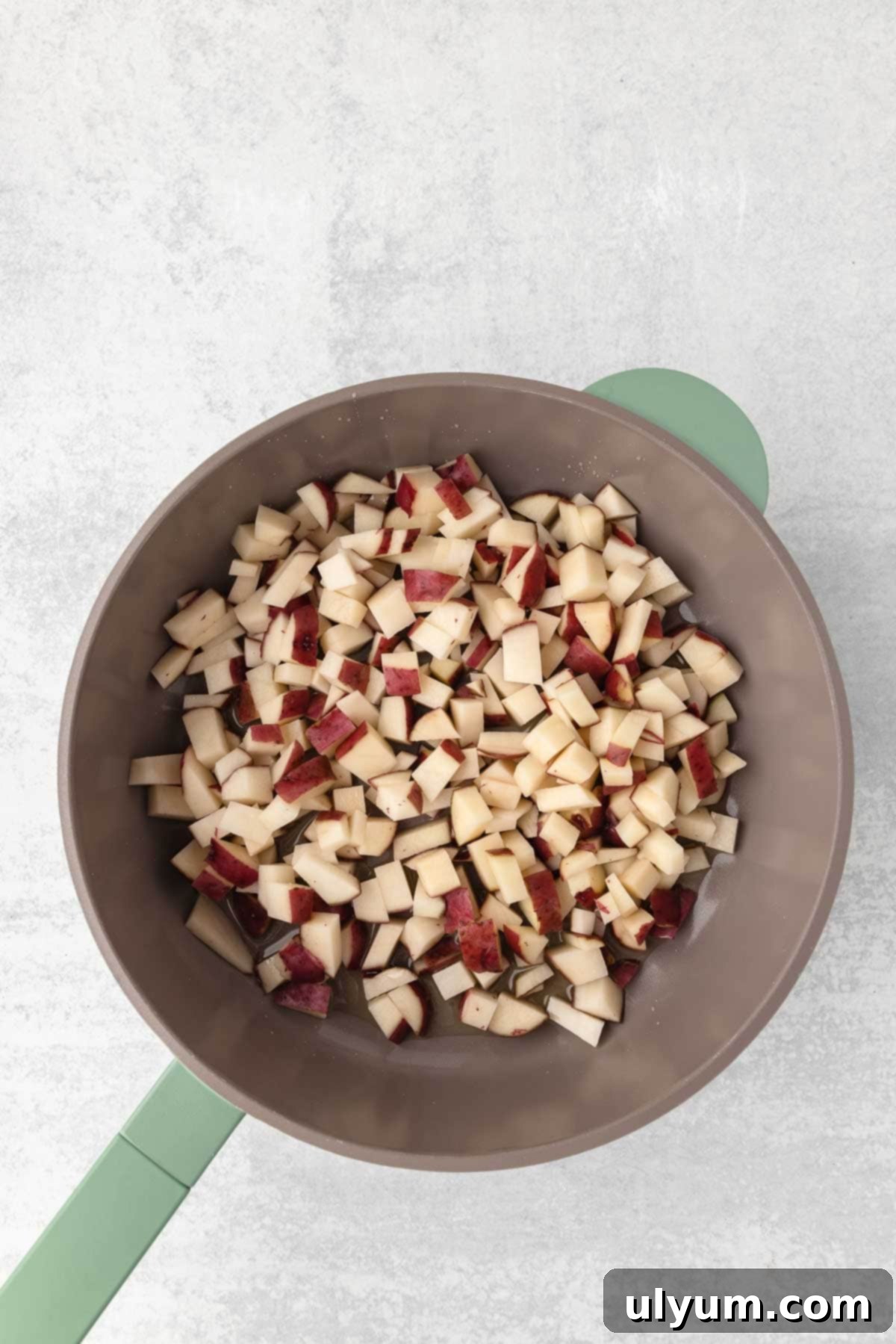 Diced red potatoes are added to the large skillet in an even layer.
