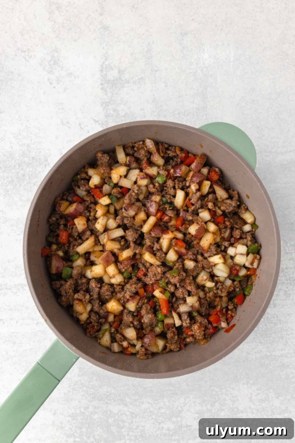 The cooked potatoes are added back to the skillet with the cooked sausage and vegetables.