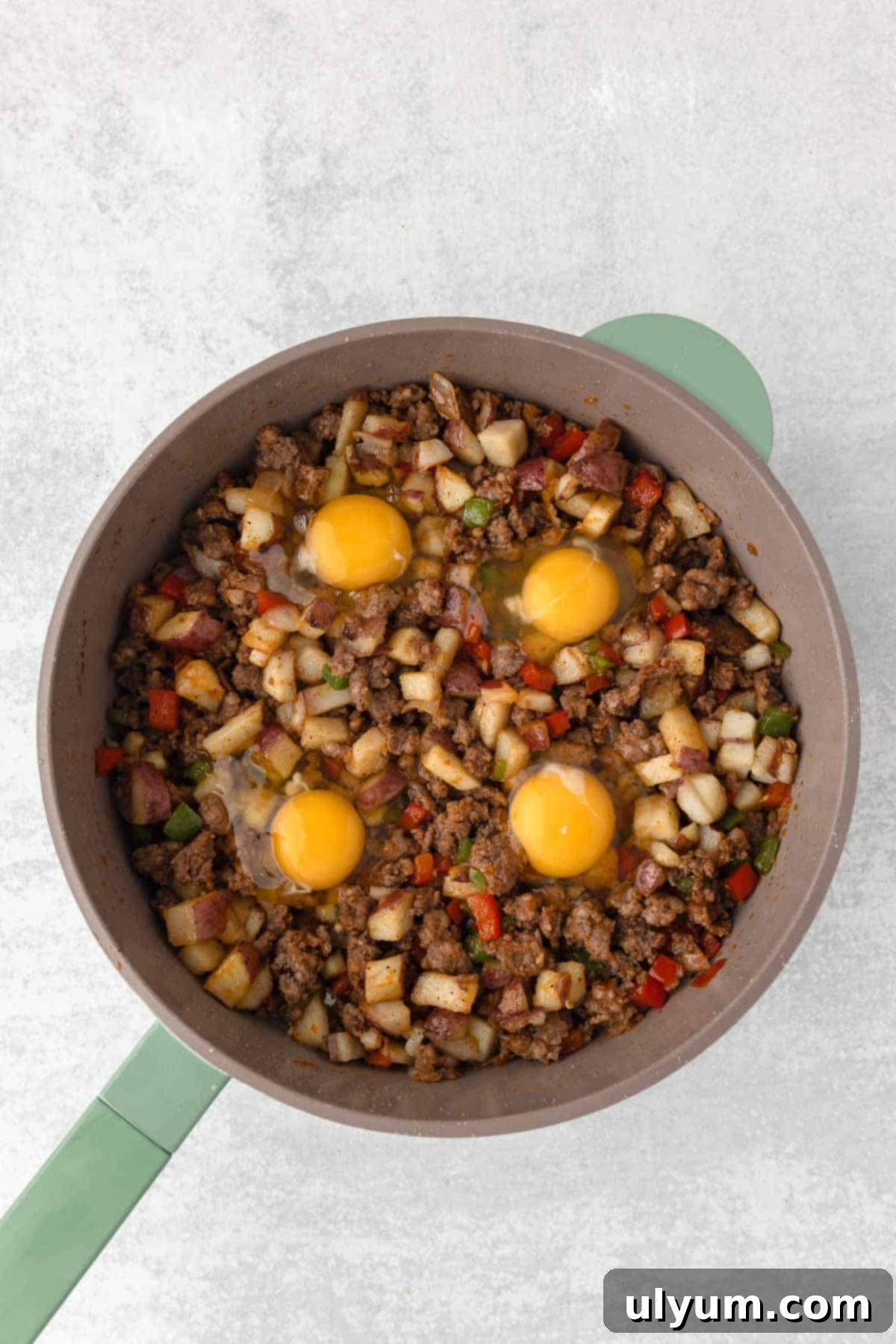 Raw eggs are cracked directly into the skillet in four evenly spaced wells.