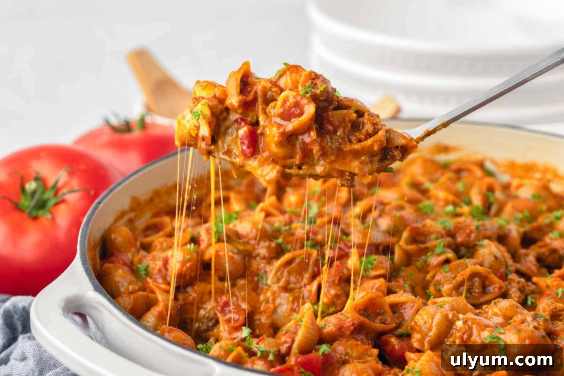 The Ultimate One-Pot Cheesy Taco Pasta 11 A serving spoon is scooping up taco pasta showcasing a satisfying cheese pull as the strings of cheese stretch from the spoon to the pot below.