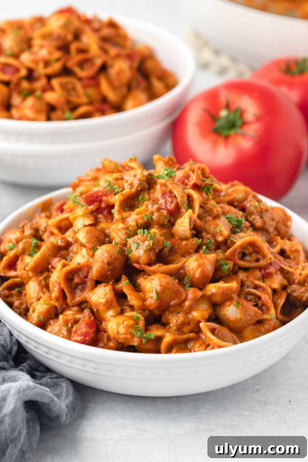The Ultimate One-Pot Cheesy Taco Pasta 12 A bowl is filled with an oversized serving of taco pasta that is garnished with fresh parsley.