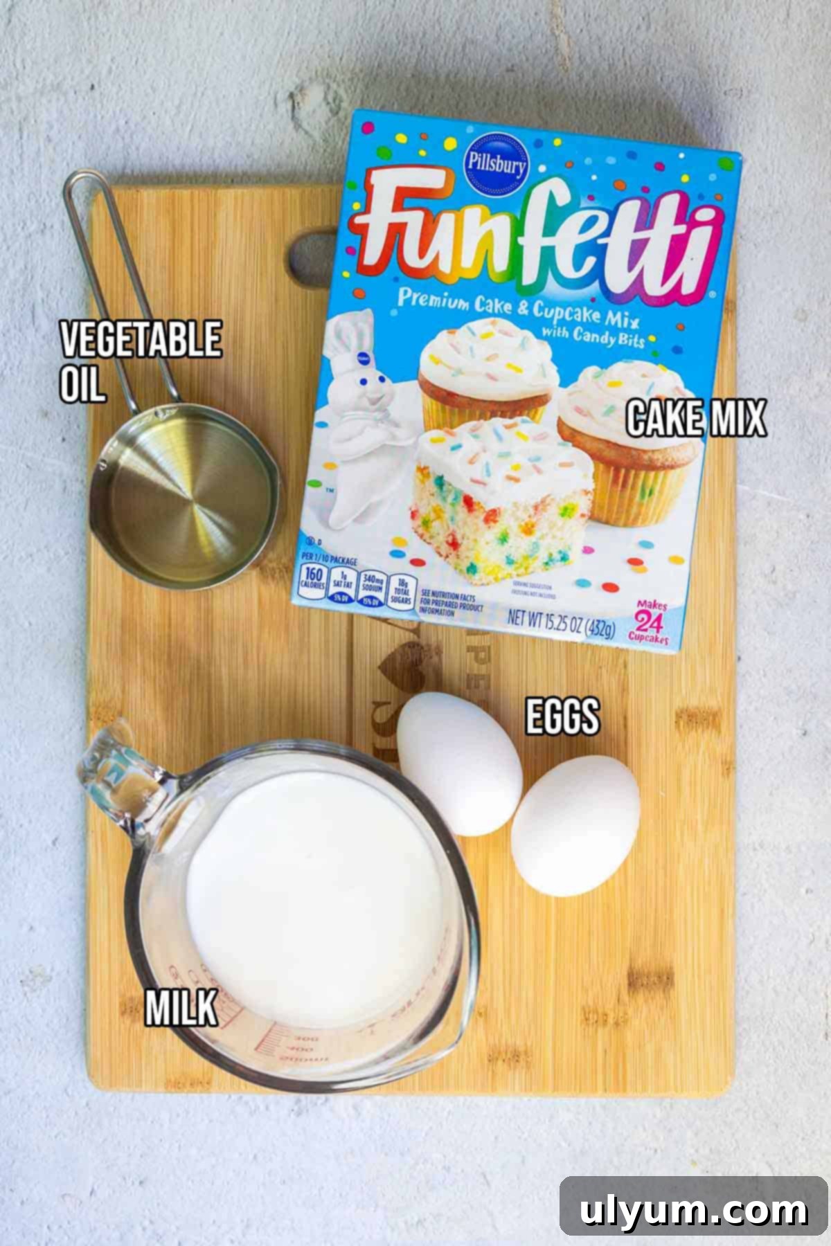 Four simple Funfetti pancake ingredients: Pillsbury Funfetti cake mix, whole milk, two eggs, and vegetable oil laid out on a kitchen counter.