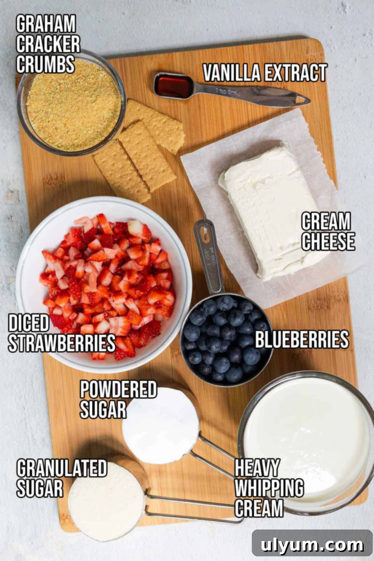 No bake cheesecake cup ingredients: heavy whipping cream, powdered sugar, vanilla extract, cream cheese, granulated sugar, graham cracker crumbs, diced strawberries, and blueberries.