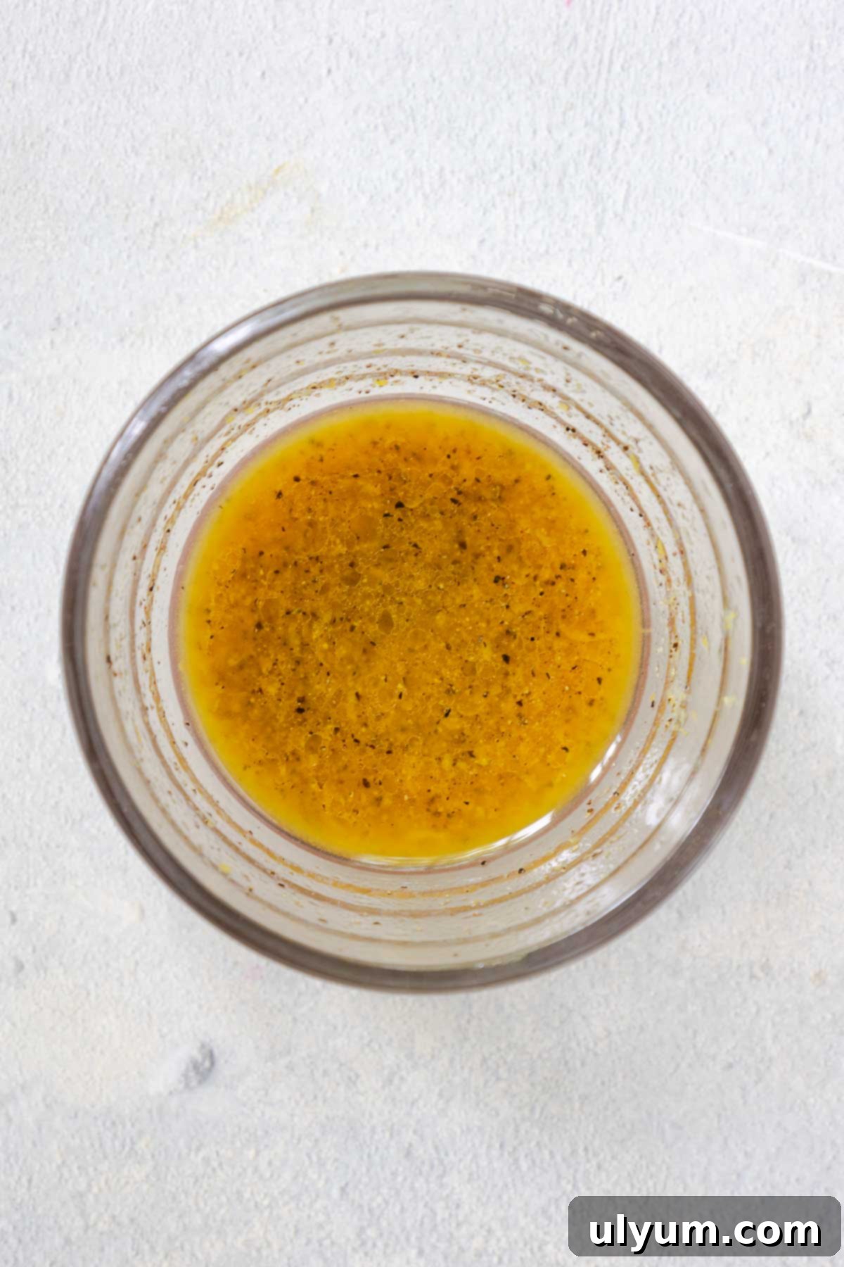 A small glass bowl containing the vibrant yellow lemon vinaigrette, mixed and ready to be used in the salad.