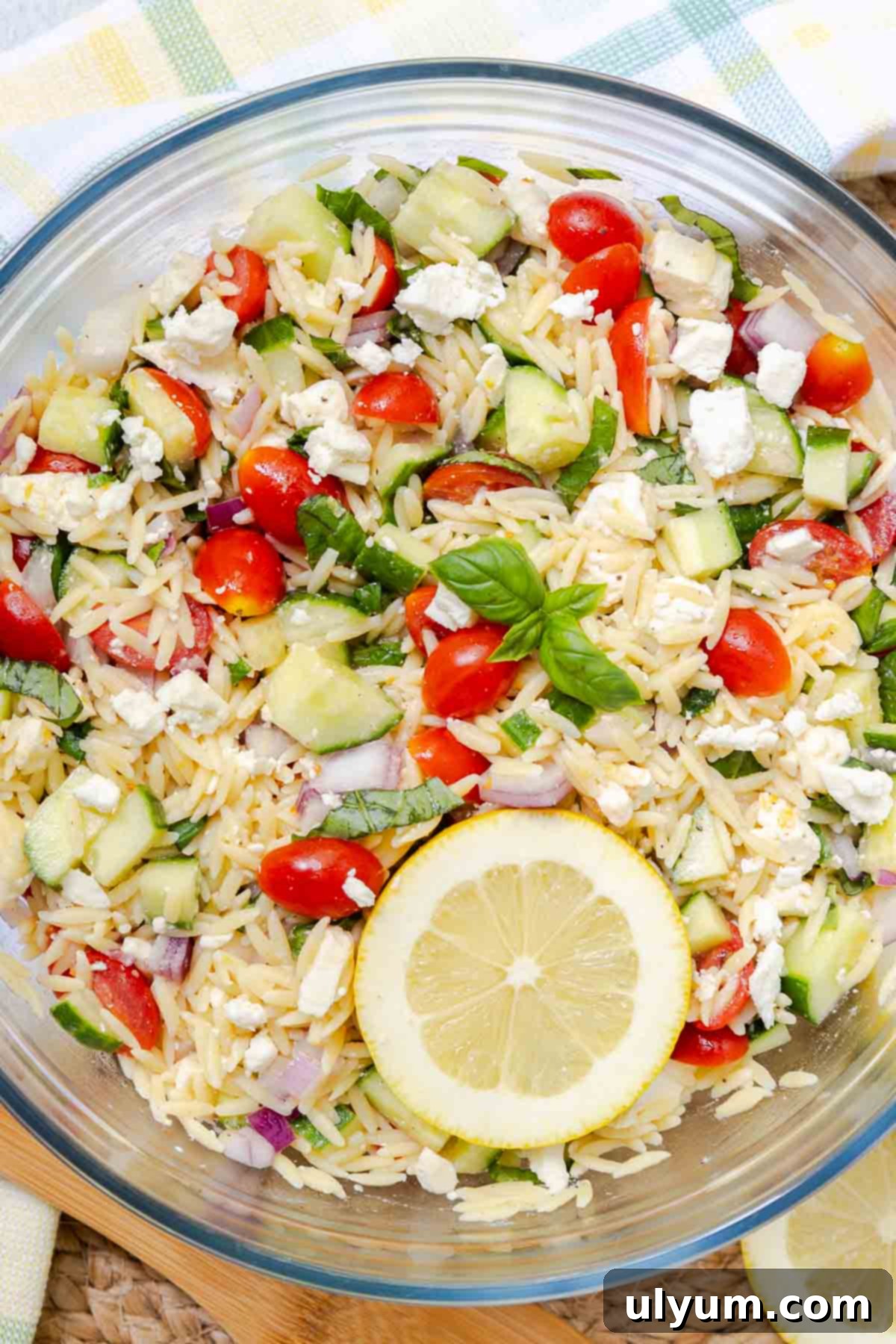 A large serving bowl filled with a colorful Lemon Feta Orzo Salad, beautifully garnished with fresh basil leaves, ready for serving at a gathering.