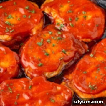 Boneless pork chops coated in BBQ sauce in a large skillet.