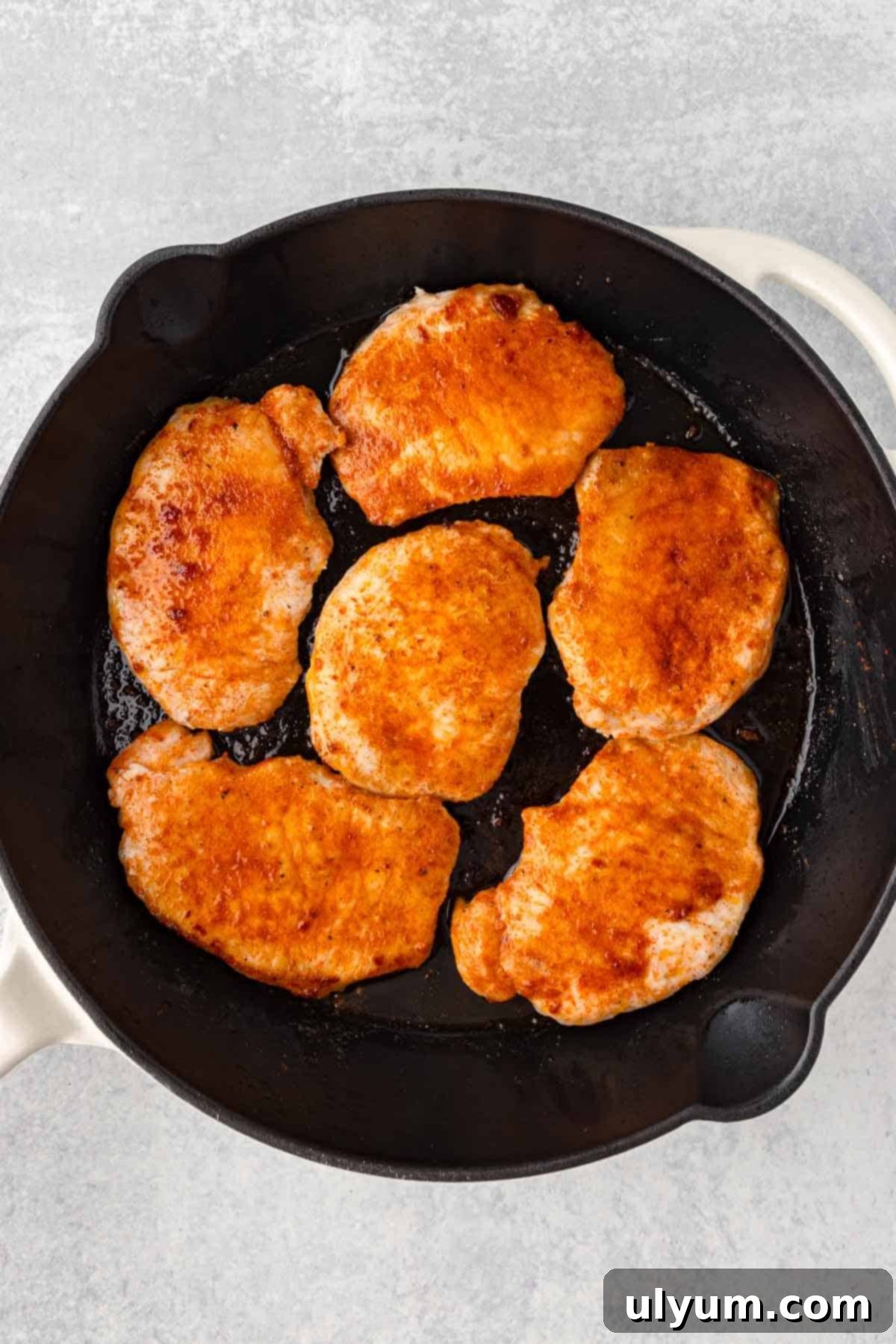 Boneless pork chops are cooked until golden brown in a large skillet.