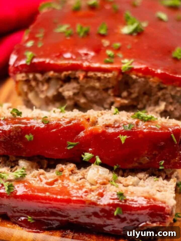 Meatloaf on a cutting board garnished with fresh parsley. Two one-inch slices are cut off the loaf.