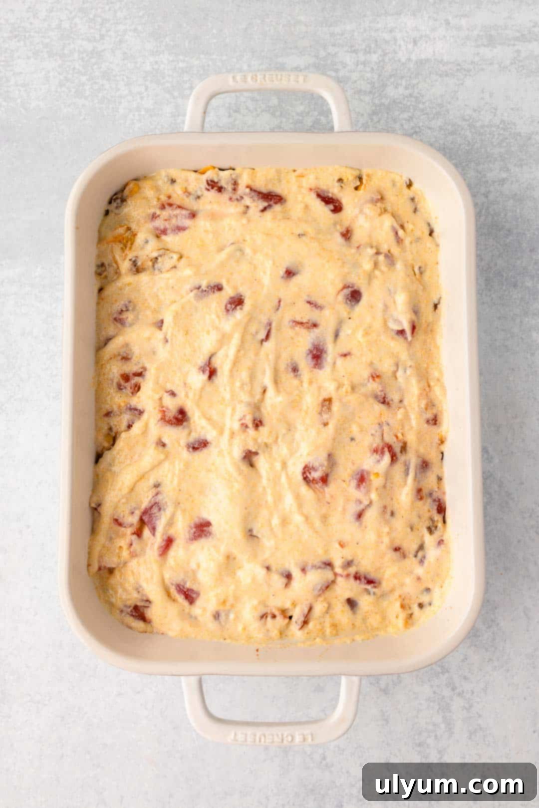 A layer of cornbread batter is spread over top all of the layers in the baking dish, creating the top crust.