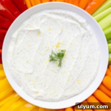 Creamy cottage cheese ranch dip on a serving platter with colorful fresh veggies including tri-color bell peppers, celery, and carrots.