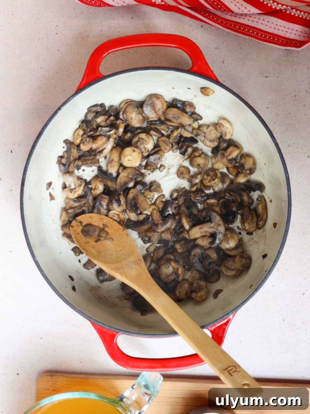 Mushrooms sautéing in a large pot until their liquid has released and evaporated, beginning to brown.