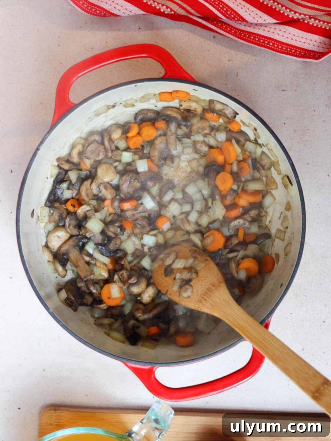 Mushrooms, onions, and carrots sautéing in a large pot until the onions are translucent and softened.
