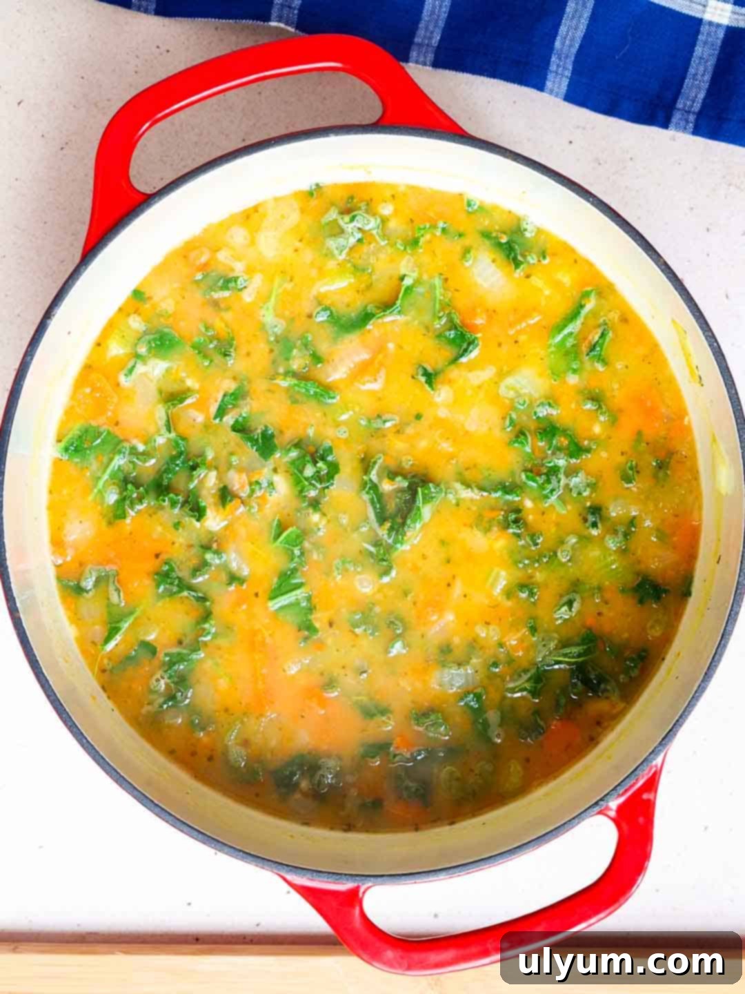 Freshly torn kale is stirred into a large pot of hot Lemony White Bean Soup until it wilts and turns bright green.