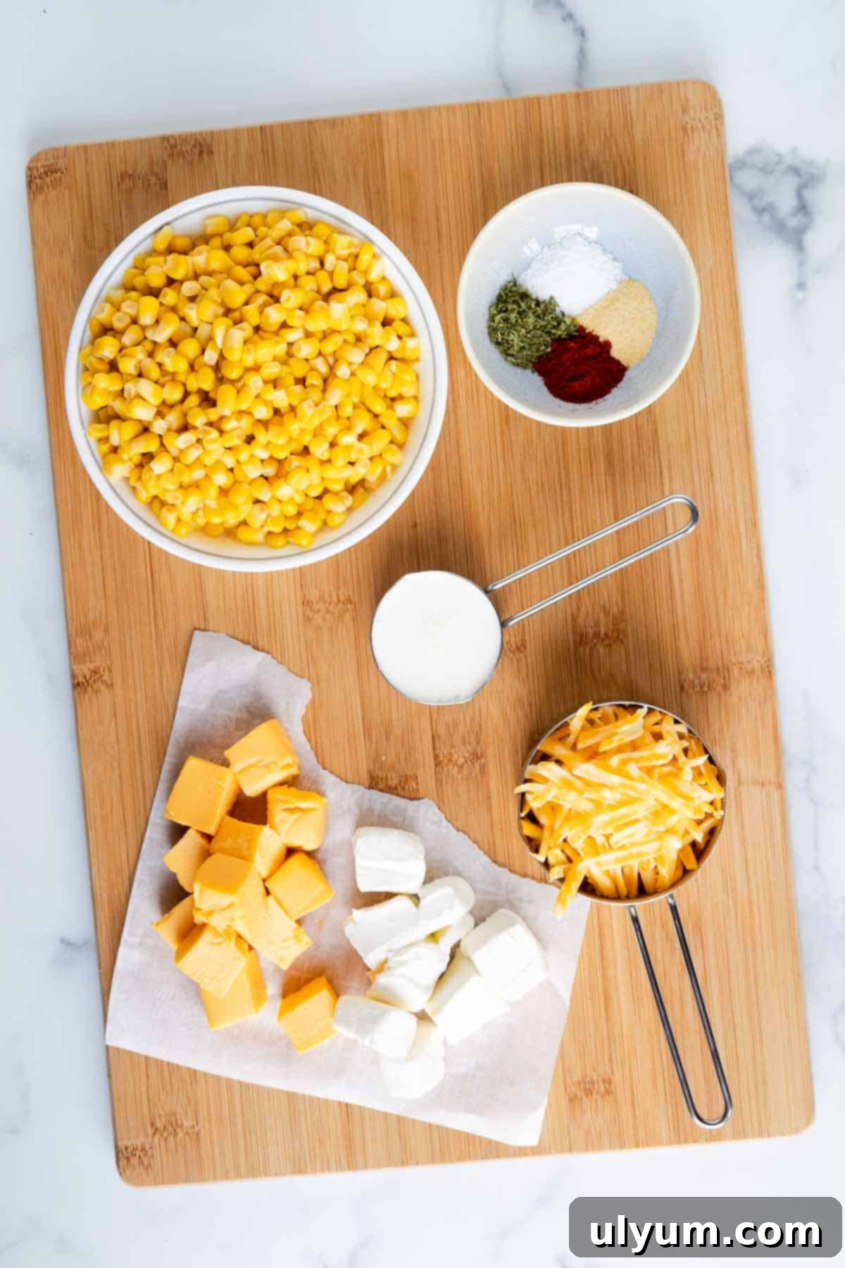 Cheesy Velveeta corn casserole ingredients: corn, cubed Velveeta, cubed cream cheese, heavy cream, garlic powder, dried parsley, kosher salt, and smoked paprika.