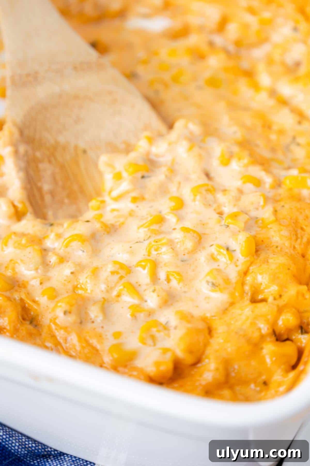 Creamy corn casserole scooped in a wooden spoon.