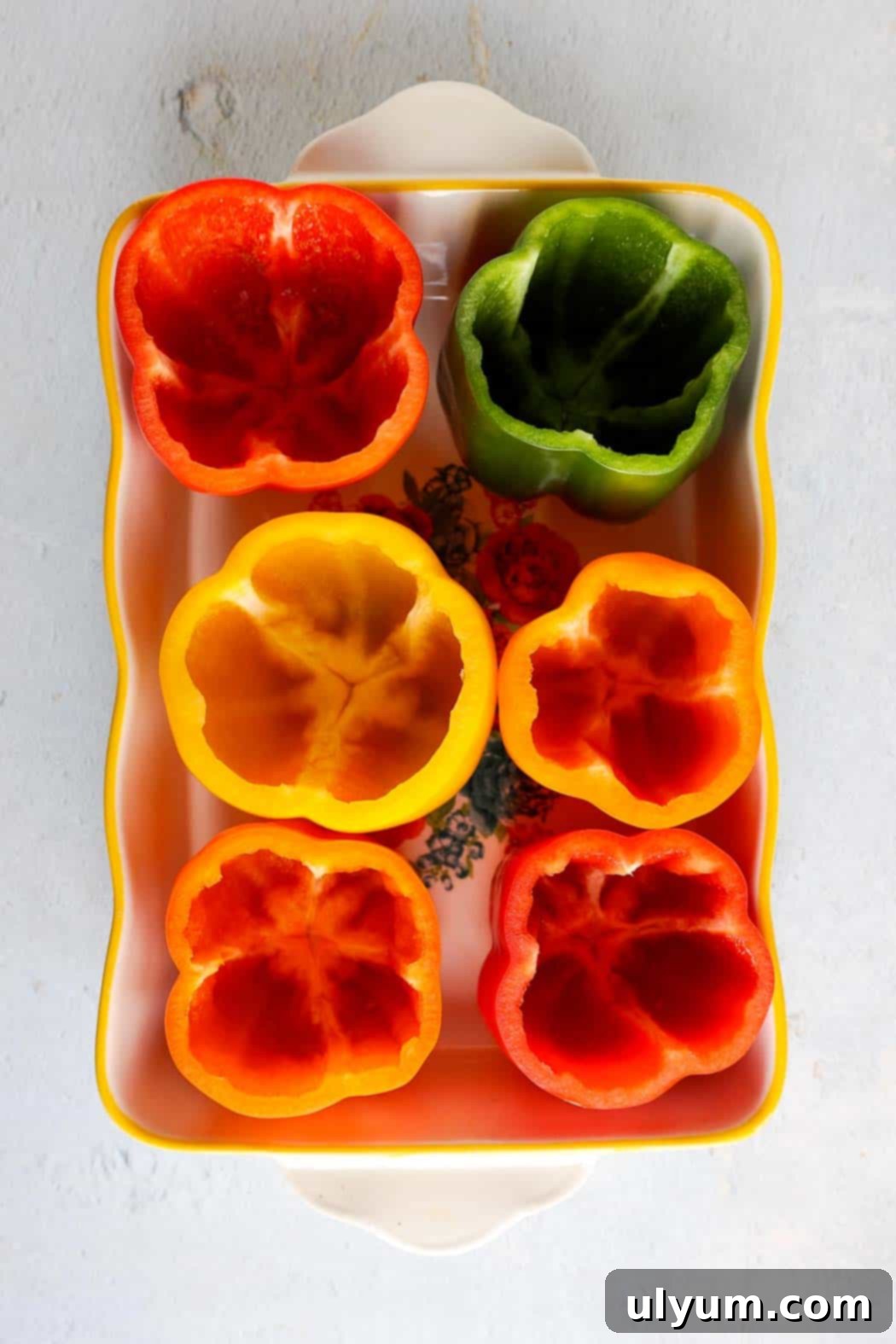 Hearty Ground Turkey and Rice Stuffed Peppers 4 Six vibrant bell peppers, including green, red, yellow, and orange, with their tops cleanly cut off and seeds removed, standing upright in a small baking dish, ready for stuffing.