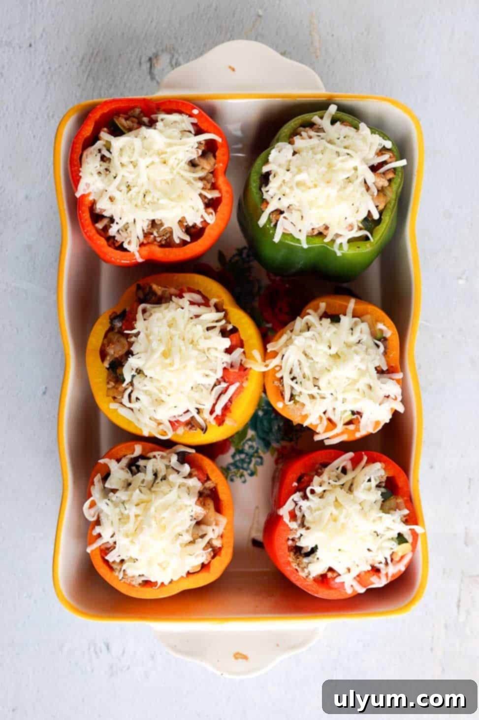 Hearty Ground Turkey and Rice Stuffed Peppers 10 Baking dish with six multicolored stuffed bell peppers, now perfectly topped with a generous layer of shredded mozzarella cheese, ready for its final bake to melt.
