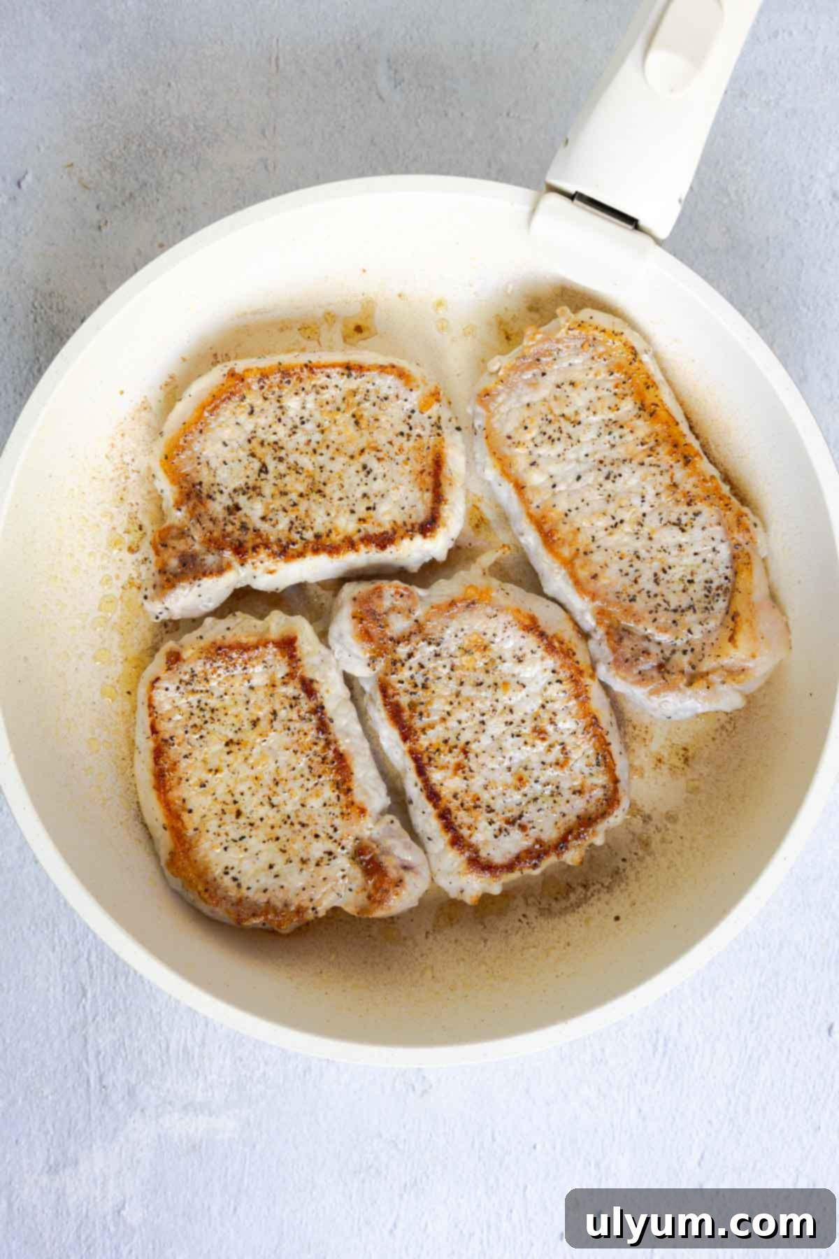 Savory French Onion Pork Chops 6 Four pork chops searing in a skillet until golden.