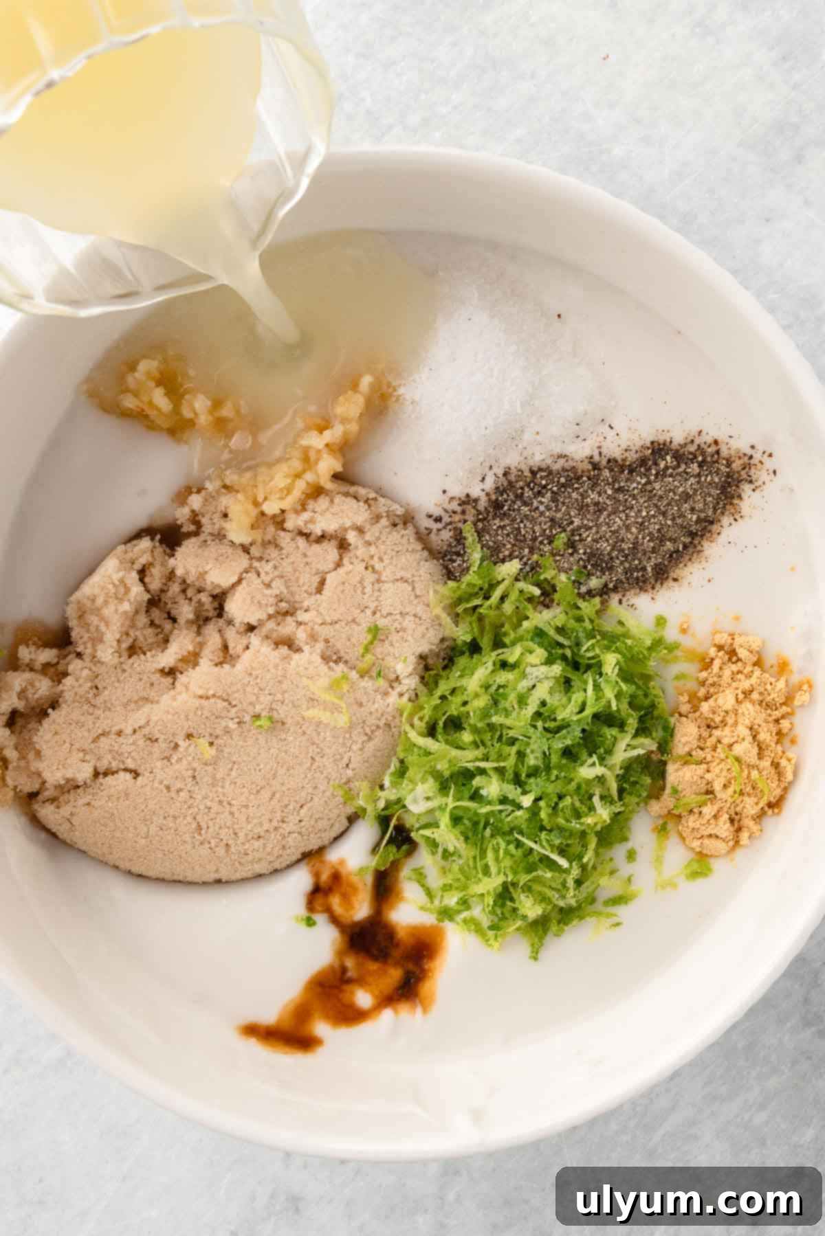 Easy One Pan Coconut Lime Chicken 4 Lime juice being poured into a bowl with garlic, brown sugar, lime zest, soy sauce, ginger, salt, and pepper.