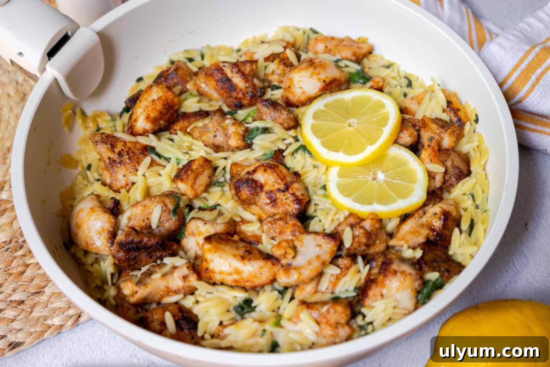 Bright Lemon Chicken Orzo Skillet 12 Seasoned diced chicken in a skillet with orzo, chopped baby spinach, and lemon slices.