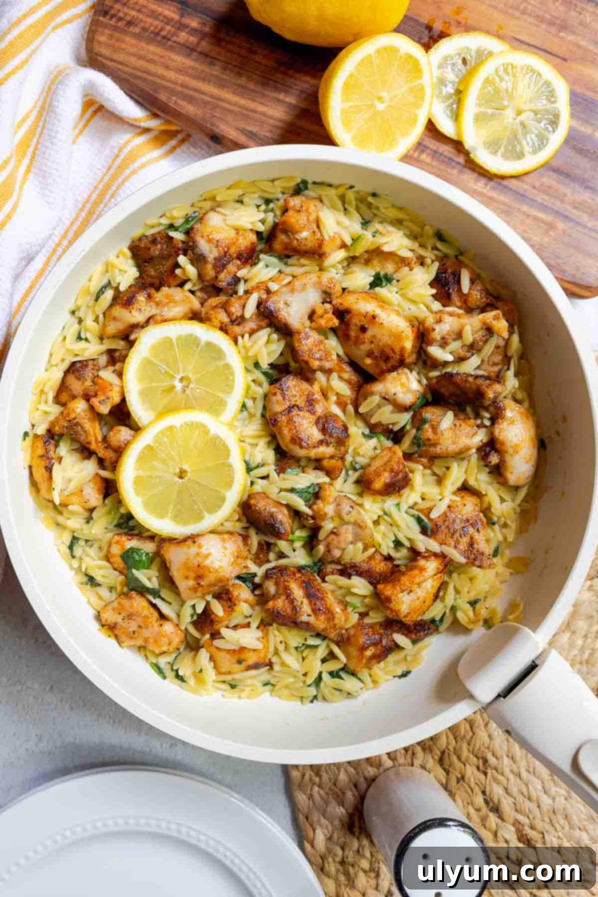 Bright Lemon Chicken Orzo Skillet 15 Seasoned diced chicken in a skillet with orzo, chopped baby spinach, and lemon slices.