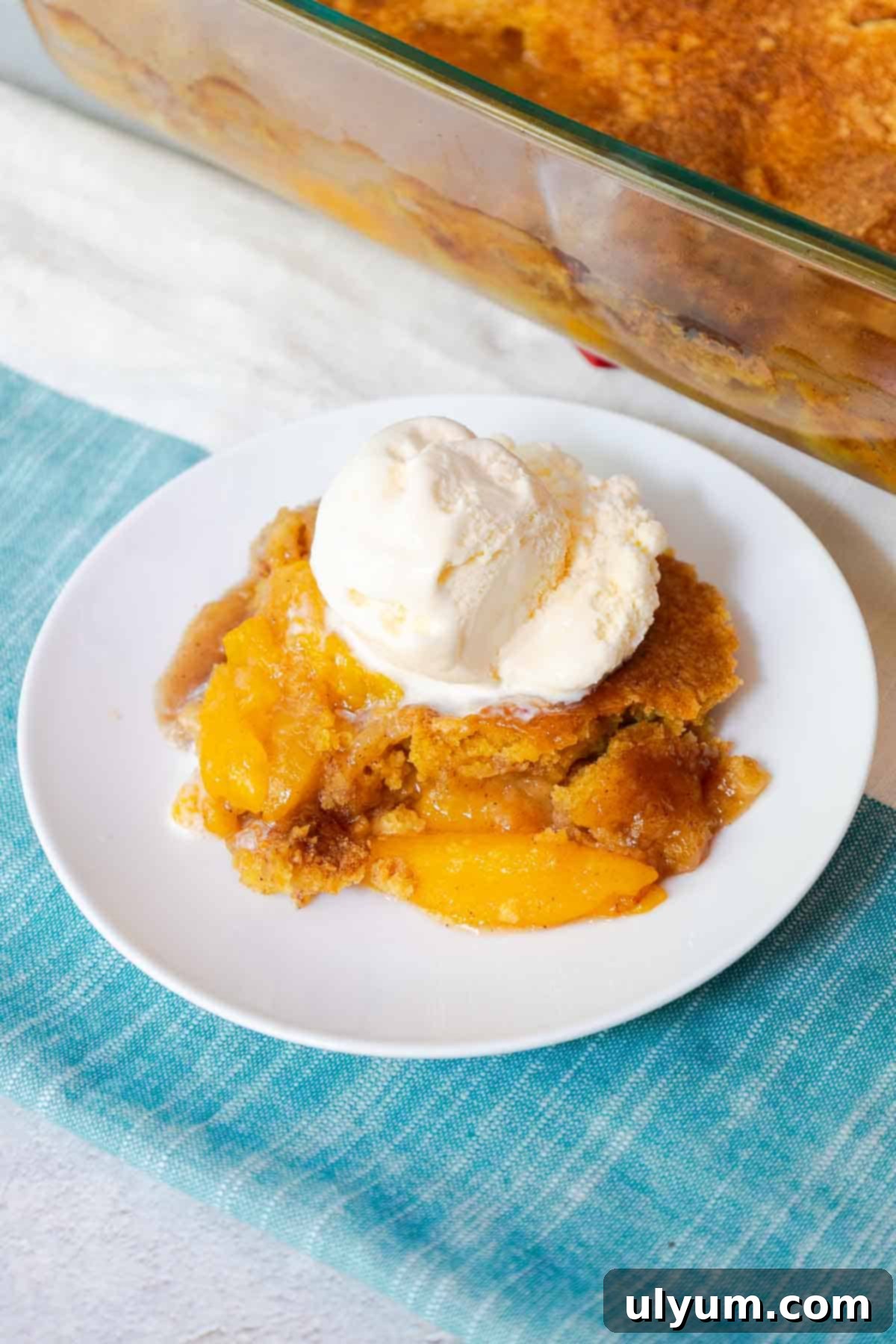Peach cobbler topped with a scoop of vanilla ice cream.