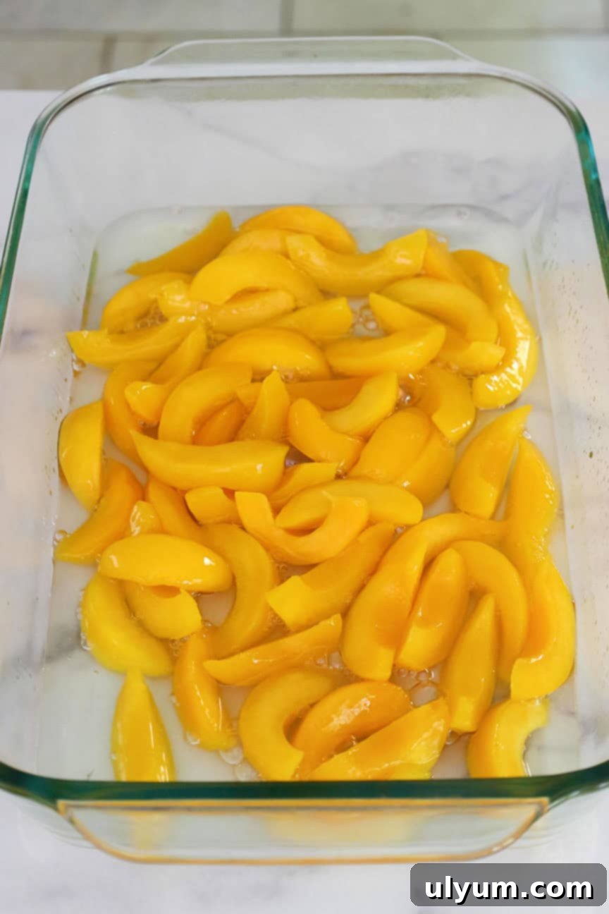 A 9 by 13 inch glass baking dish with sliced peaches in syrup.