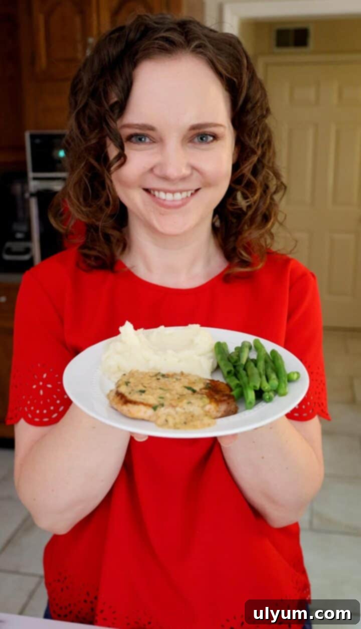 Kelsey Smith holding a plate of creamy garlic pork chops.