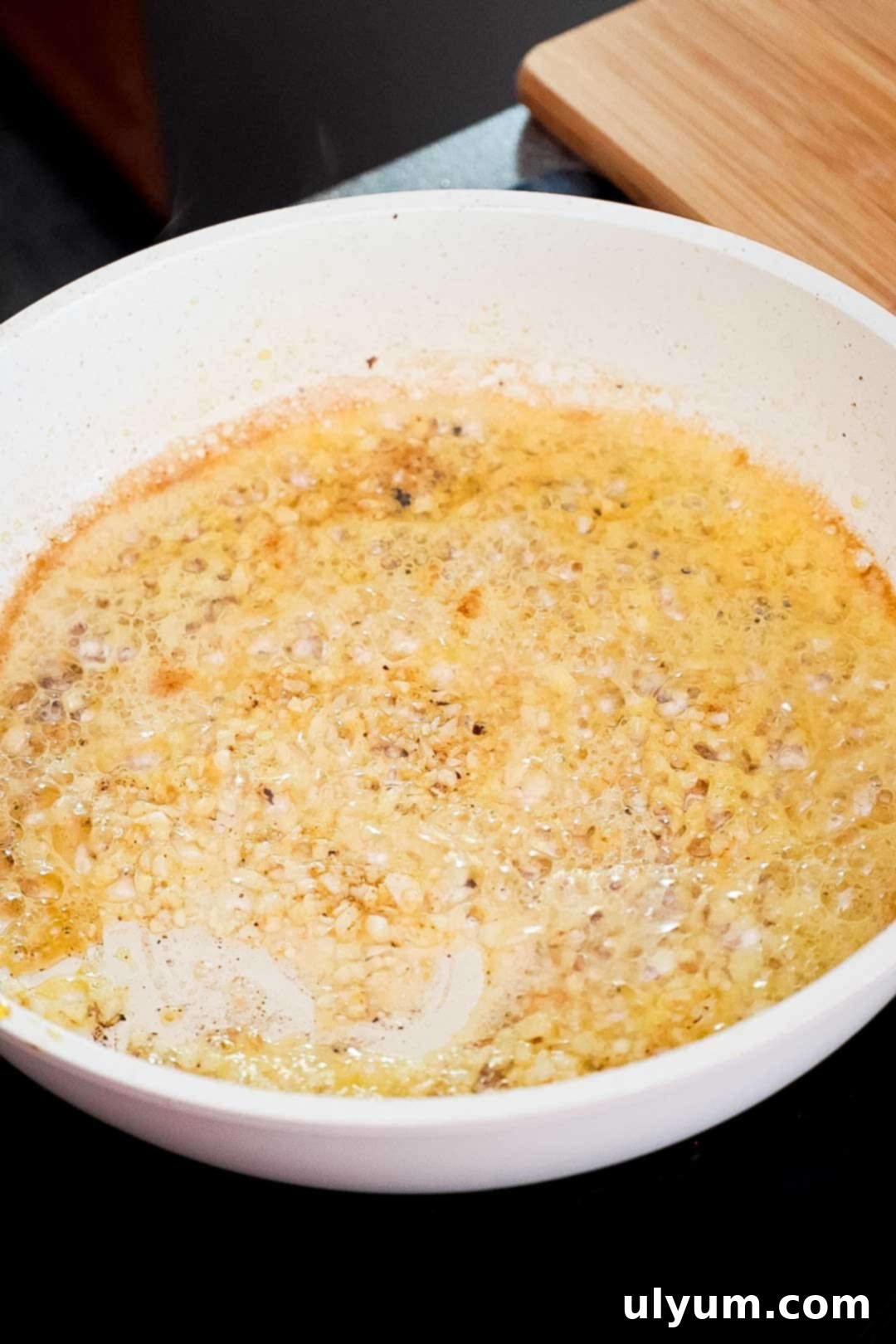 Minced garlic sizzling in butter and oil in a skillet.