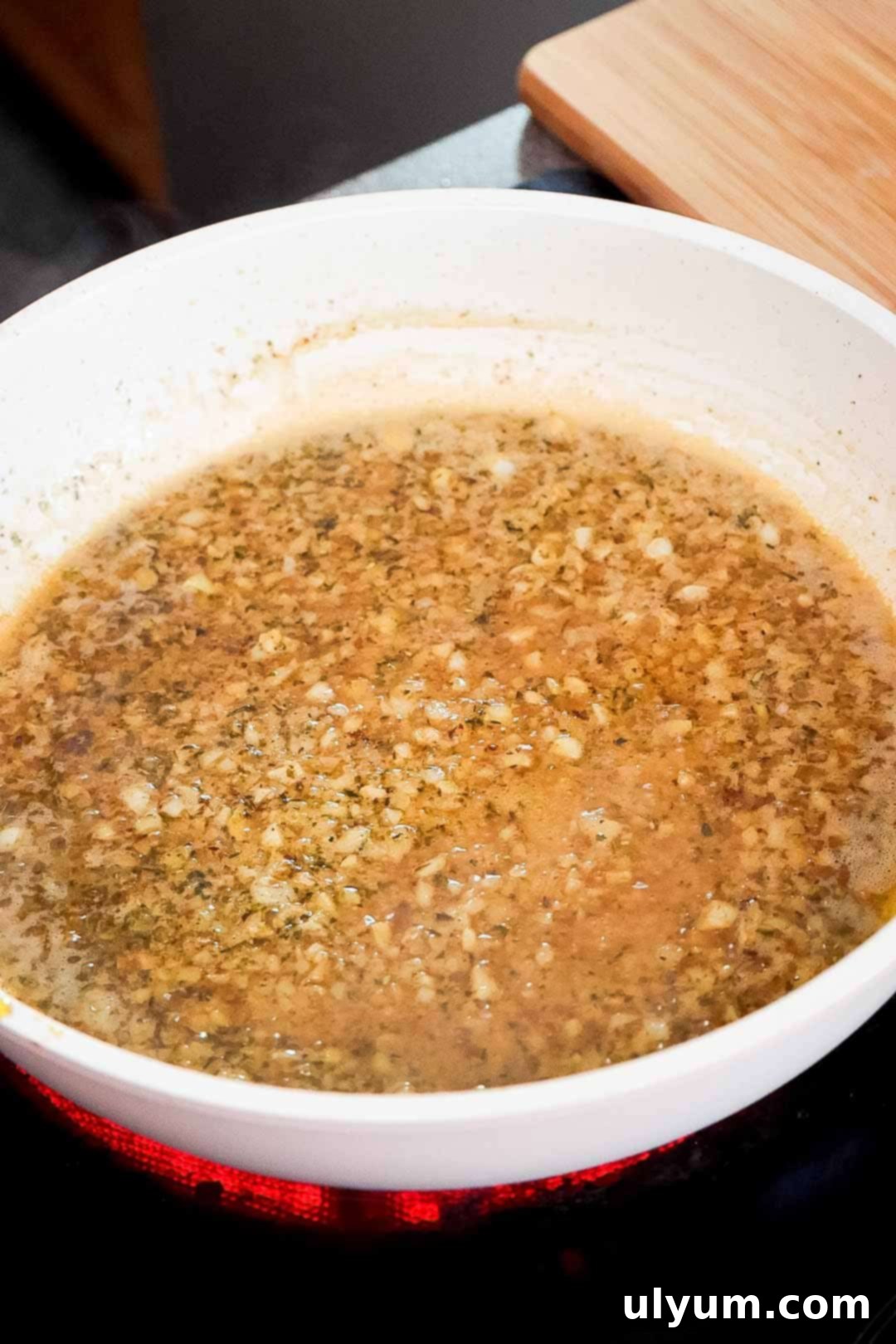 Broth, Italian seasoning, and minced garlic simmering in a skillet.