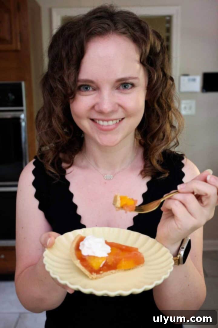 Kelsey Smith holding a plate with a slice of peach Jello pie, showcasing the beautiful dessert.