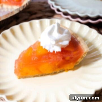 Peach jello pie with peach chunks set in peach gelatin in a graham cracker pie crust topped with whipped topping.