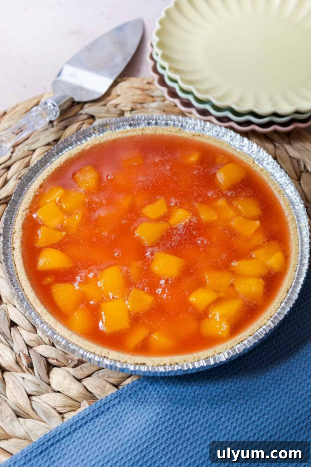 A finished peach Jello pie with peach chunks set in peach gelatin in a graham cracker pie crust, ready for chilling.