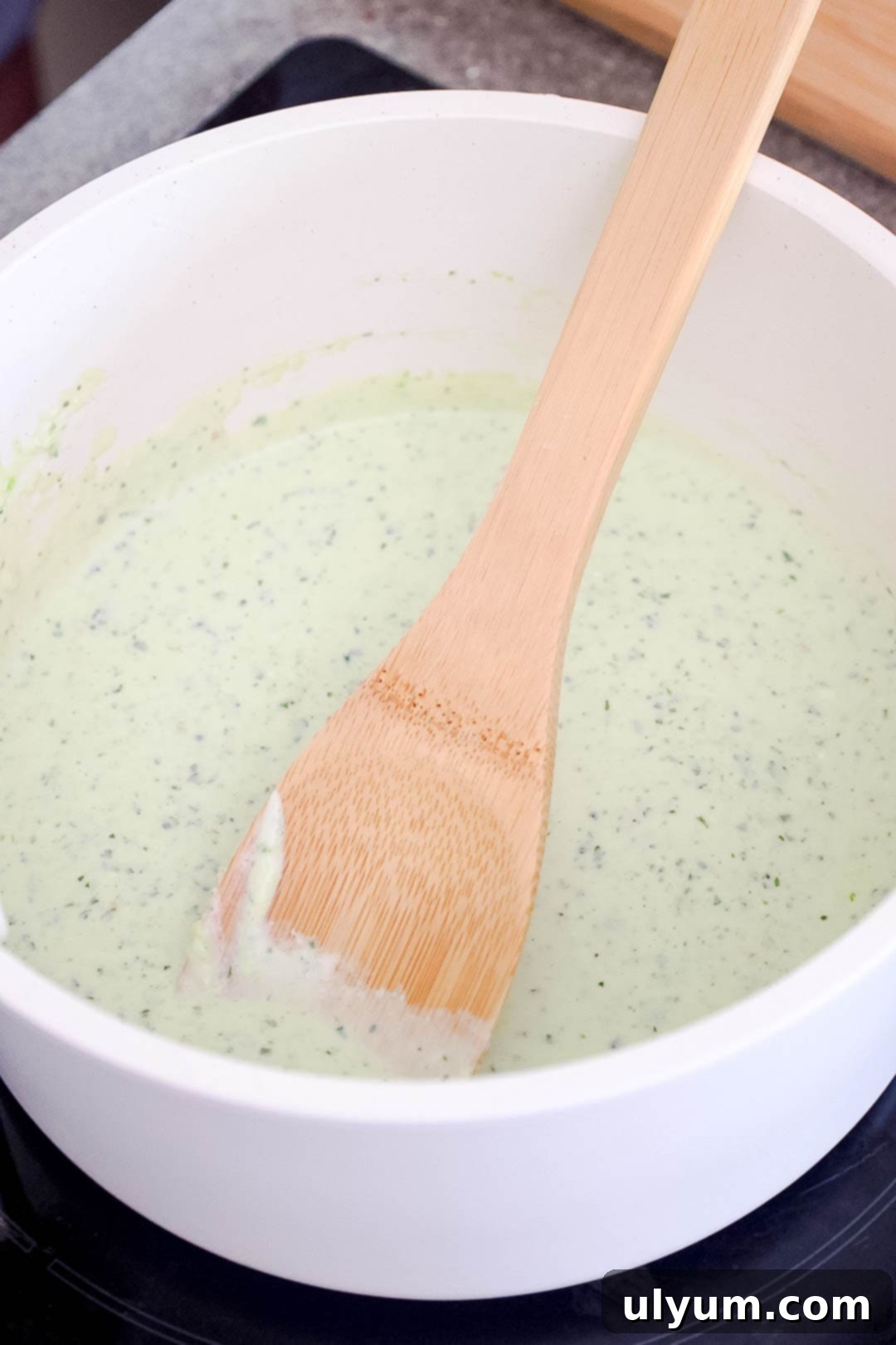 Spicy Creamy Jalapeño Ranch Pasta 7 A saucepan with creamy jalapeño sauce and a wooden spoon.
