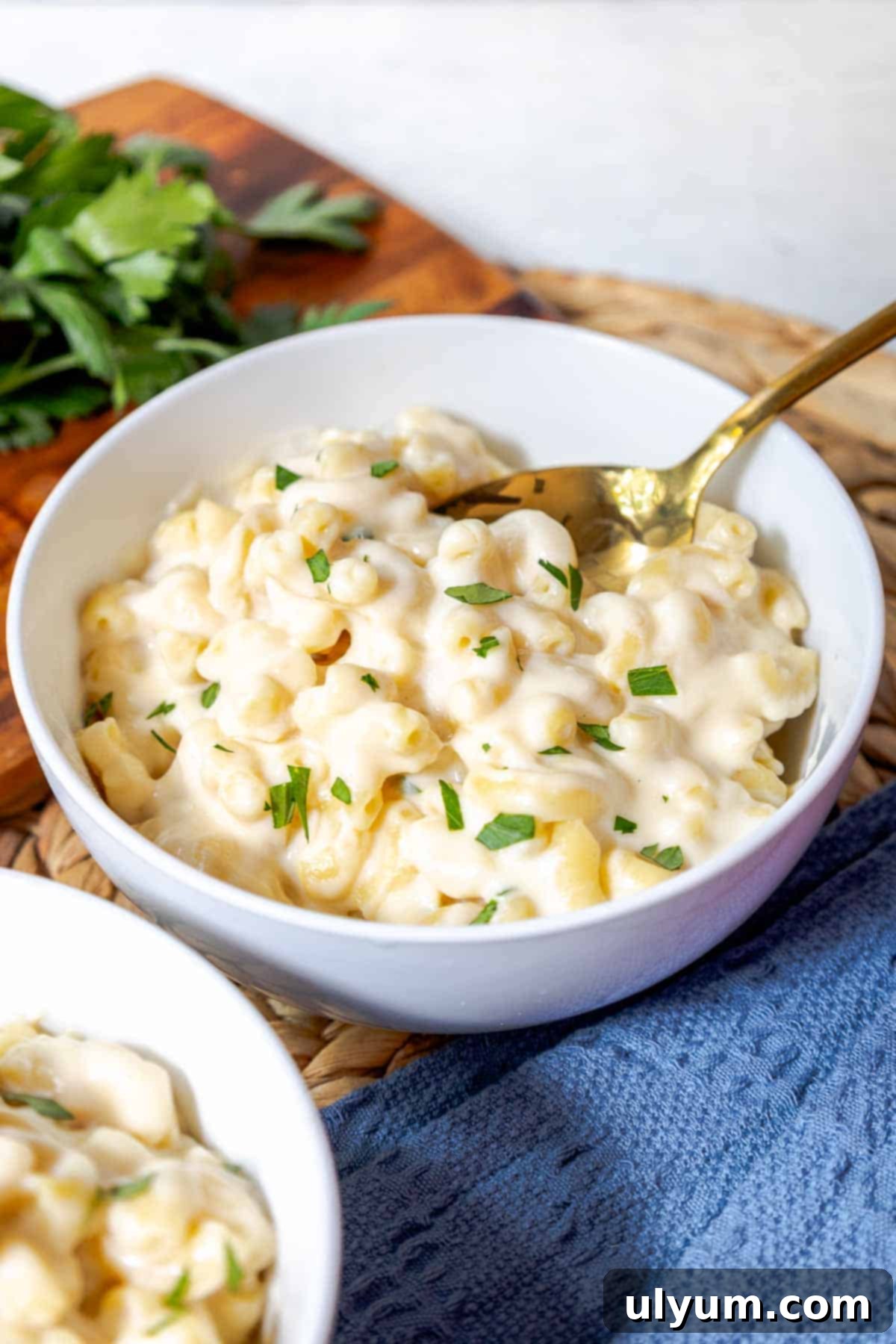 A bowl of creamy white cheddar mac and cheese topped with fresh chopped parsley, invitingly ready to be eaten.