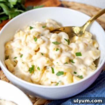 A bowl of creamy white cheddar mac and cheese topped with chopped parsley, ready for a comforting meal.