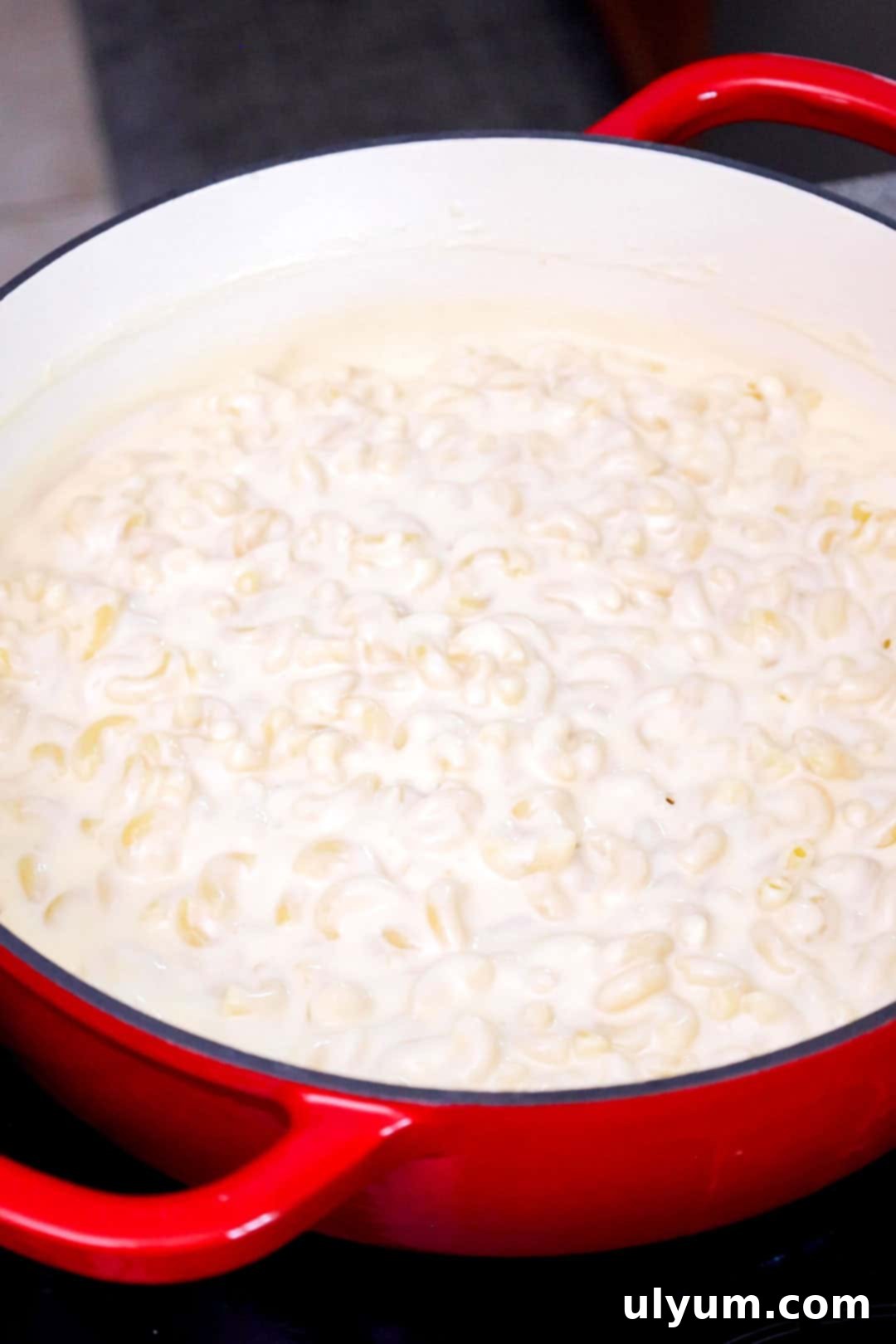 Cooked elbow macaroni in a large pot, generously coated with the rich, white cheddar cheese sauce, ready for serving.