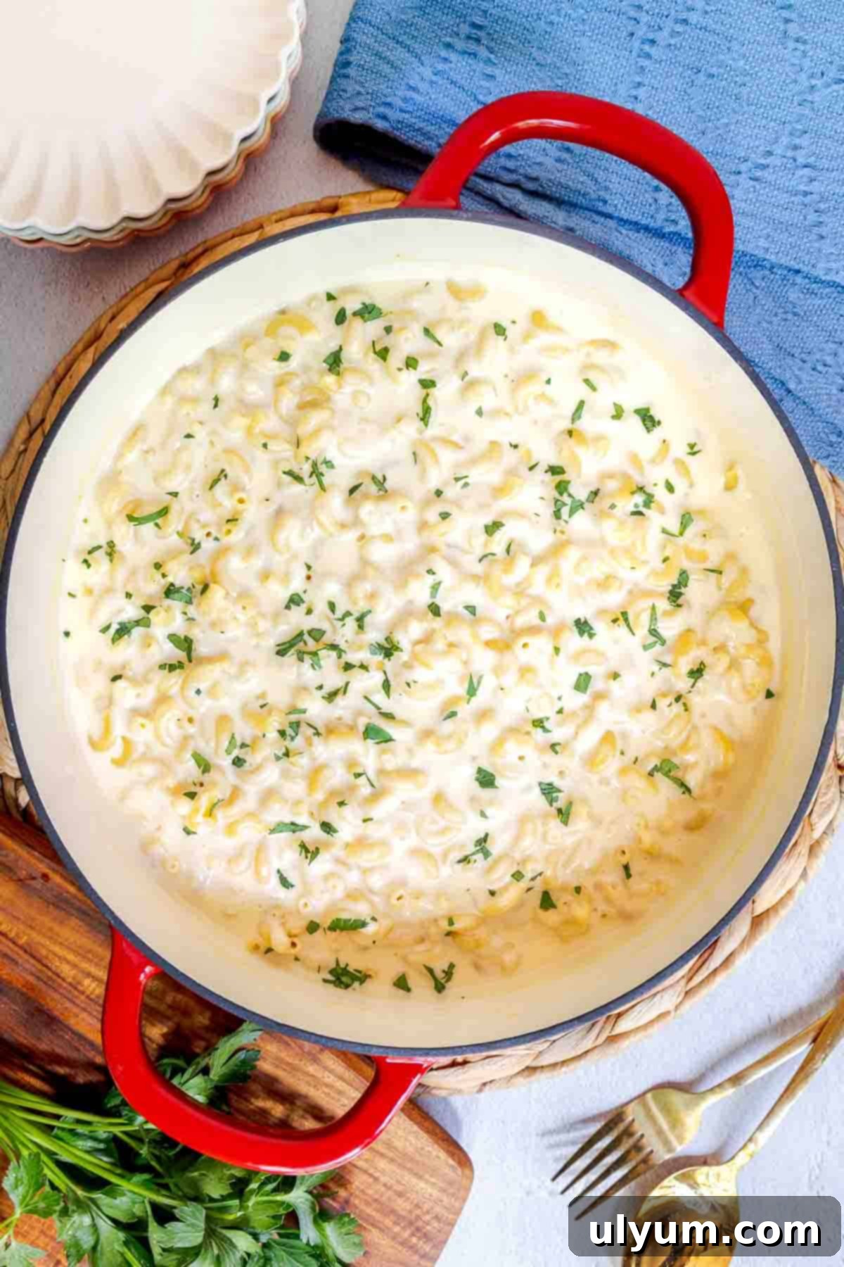 A pot of white cheddar mac and cheese, perfectly creamy and ready to serve, garnished with fresh chopped parsley.