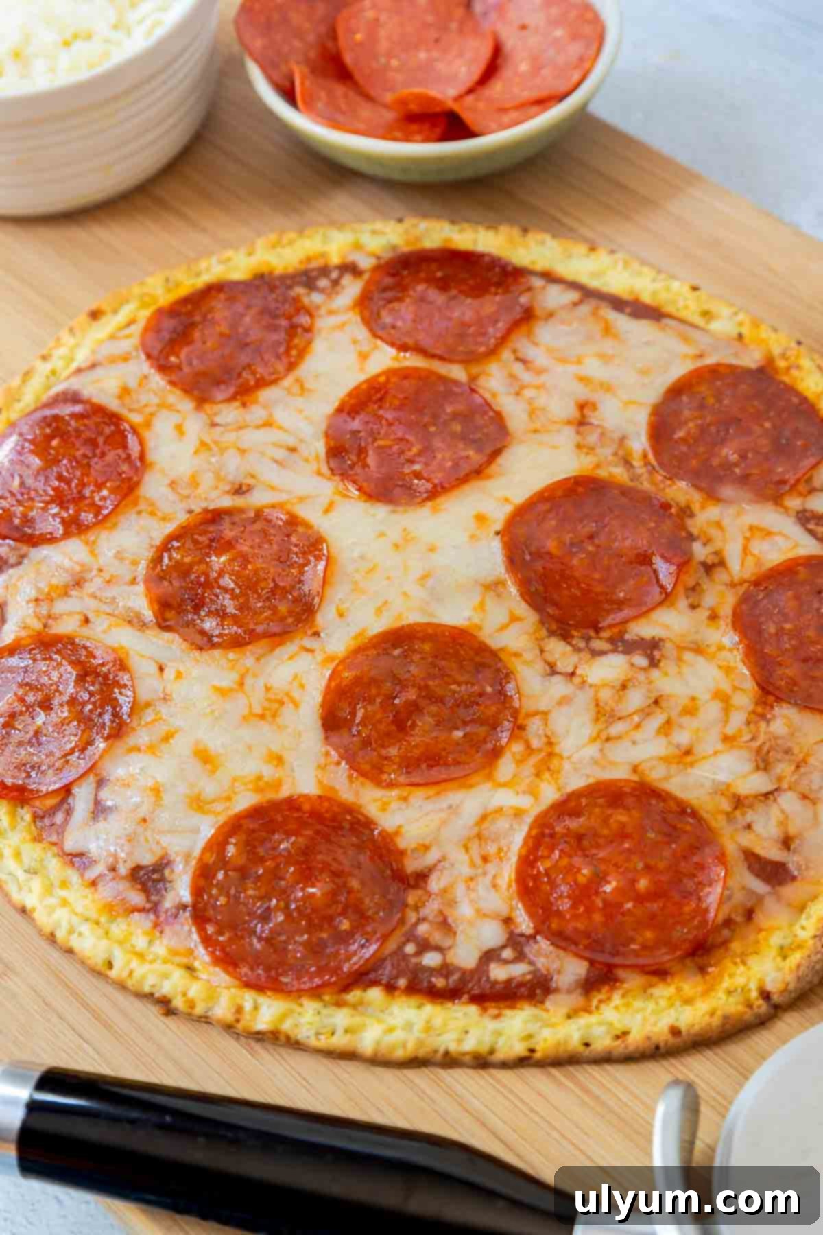 A cooked pepperoni pizza with a golden brown cottage cheese crust on a cutting board, ready to be sliced.