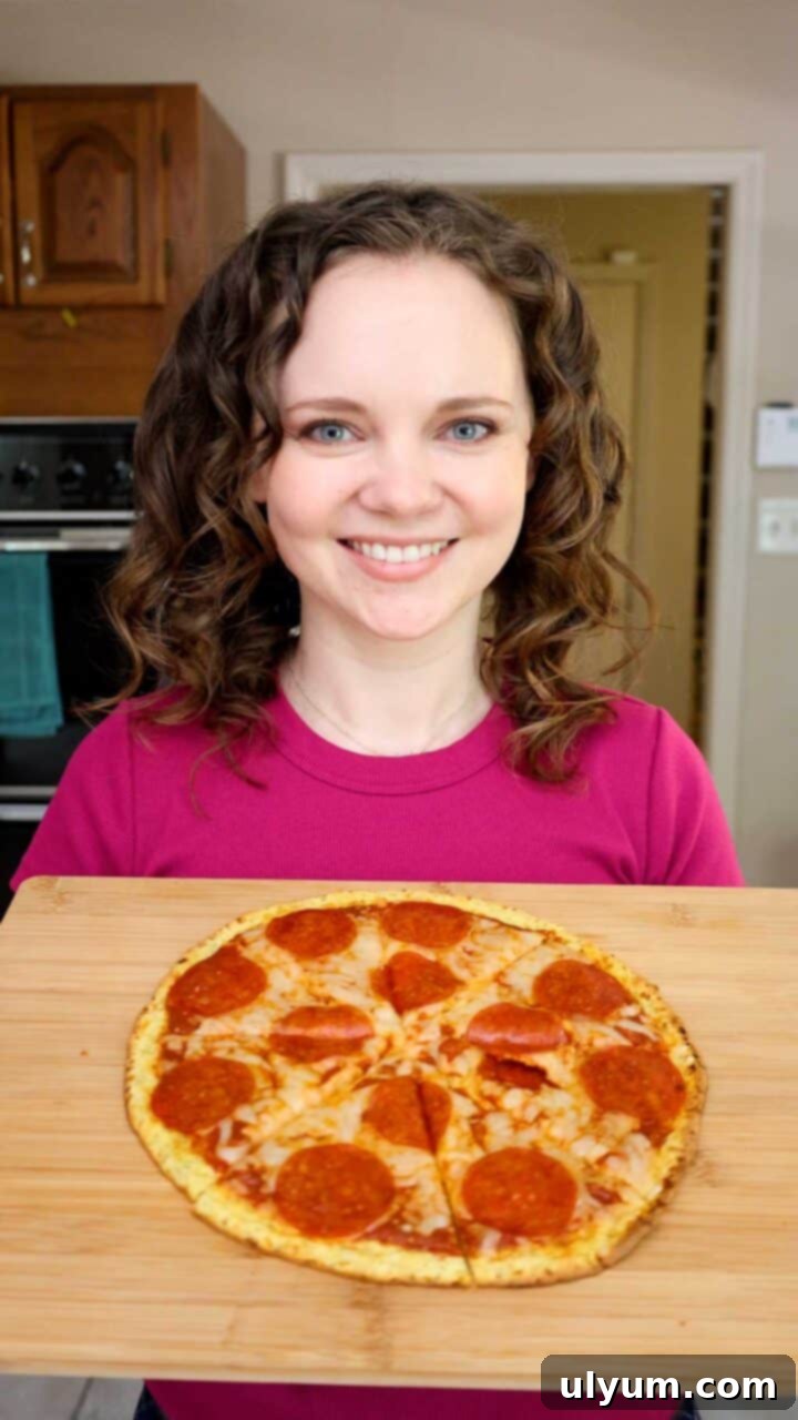 Kelsey Smith happily holding a cutting board with a freshly baked pepperoni pizza made with a cottage cheese crust.
