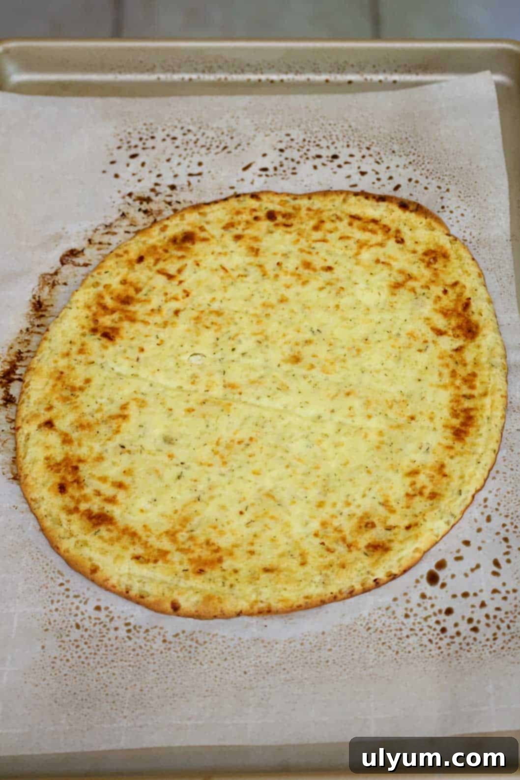 A perfectly browned and crispy pizza crust cooling on a baking sheet, ready for toppings.