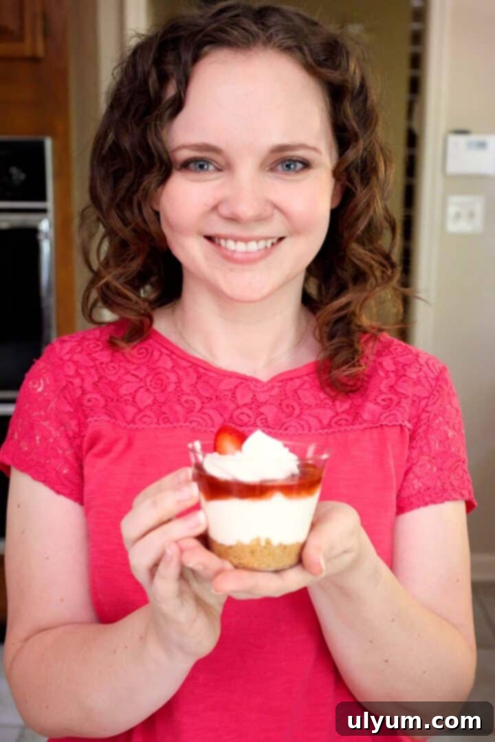 Kelsey Smith holding a strawberry cheesecake cup, showing the layers of the dessert.