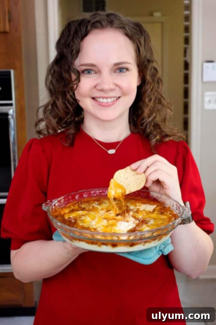 Kelsey Smith holding a dish of cream cheese chili cheese dip.