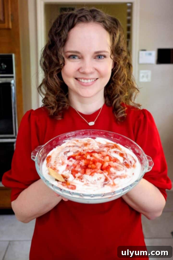 Kelsey Smith holding a pie dish of strawberry cheesecake dip.