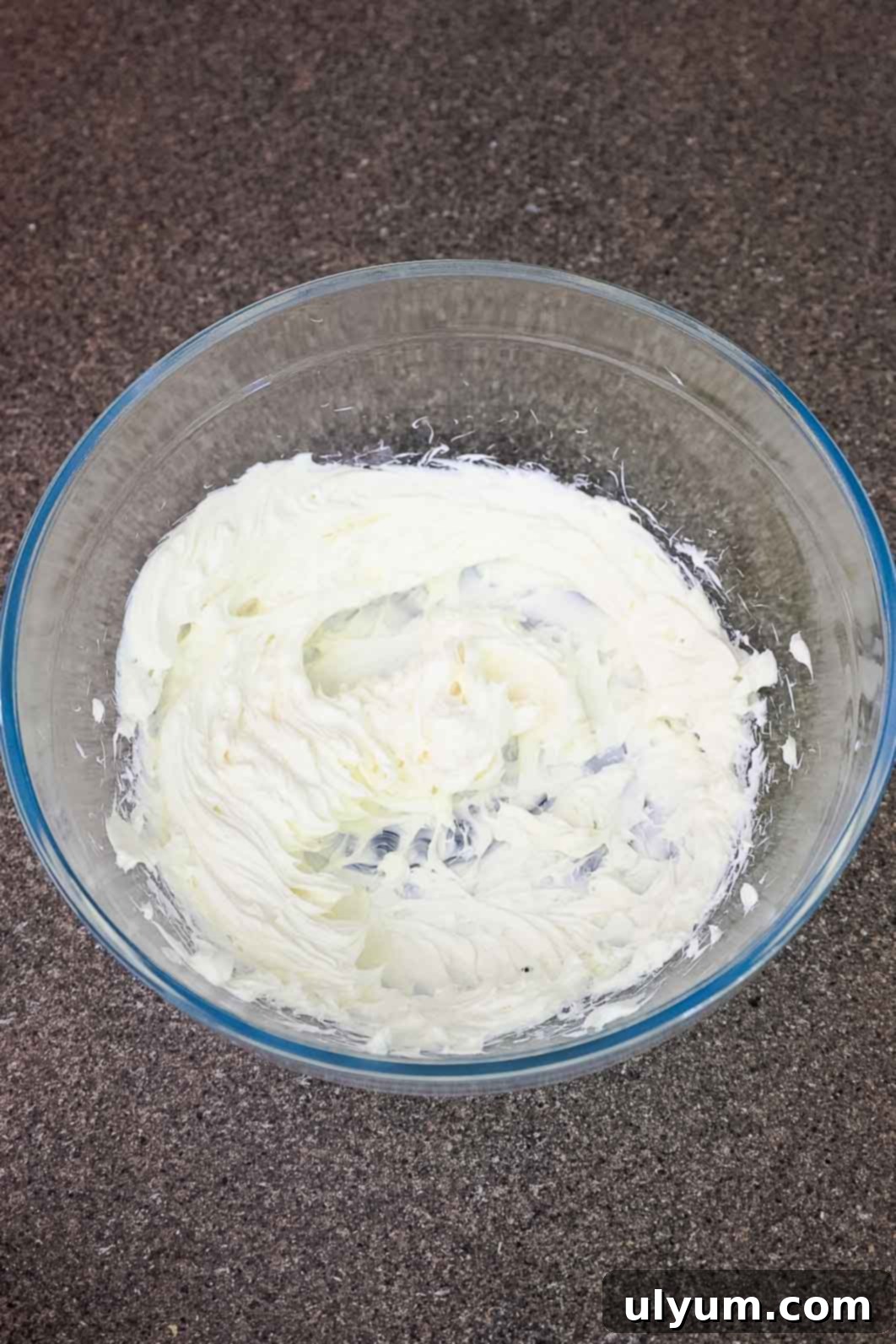 Cream cheese whipped in a glass mixing bowl.