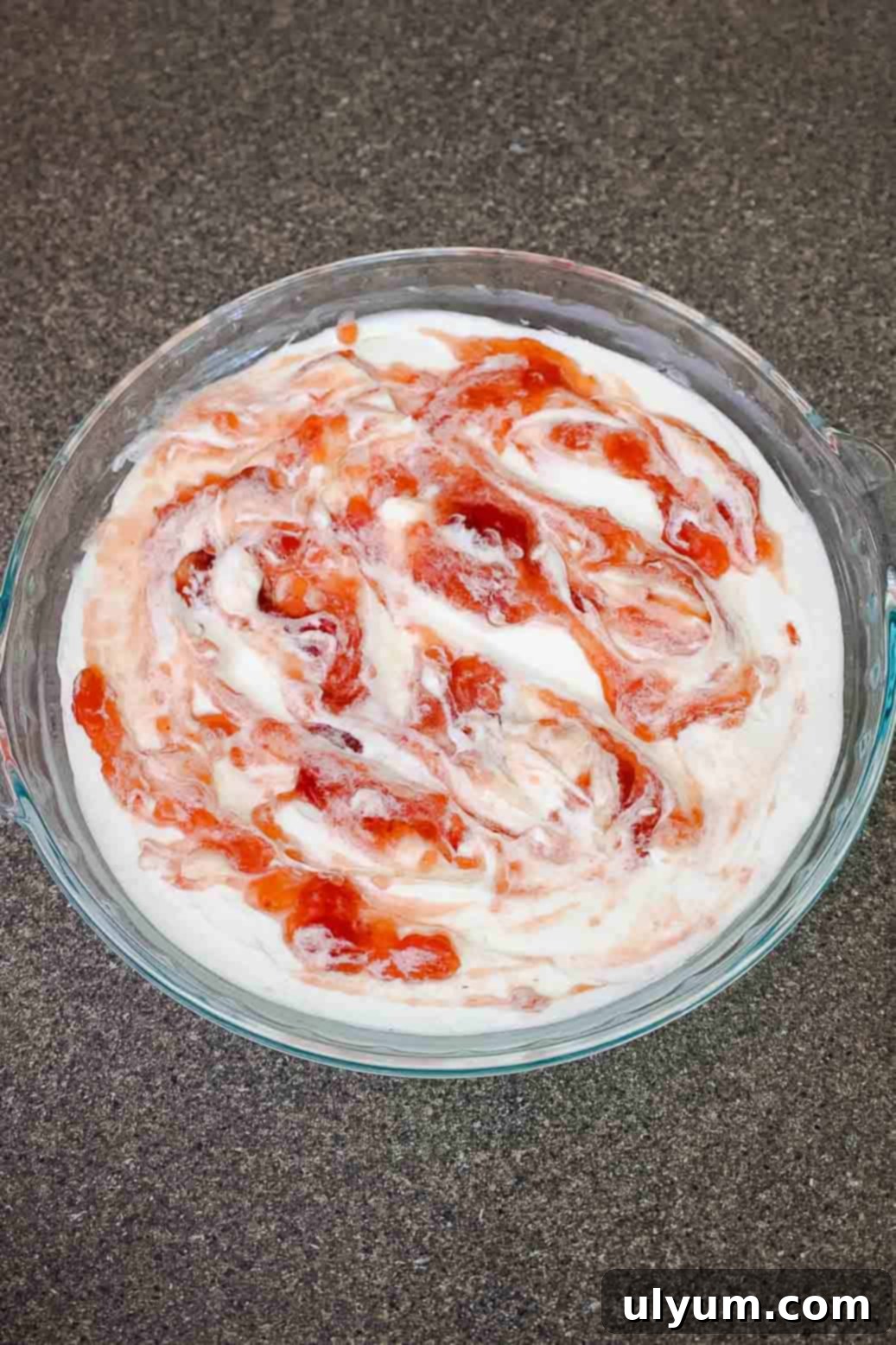 Cream cheese dip mixture with strawberry jam swirled into the top in a marble pattern.
