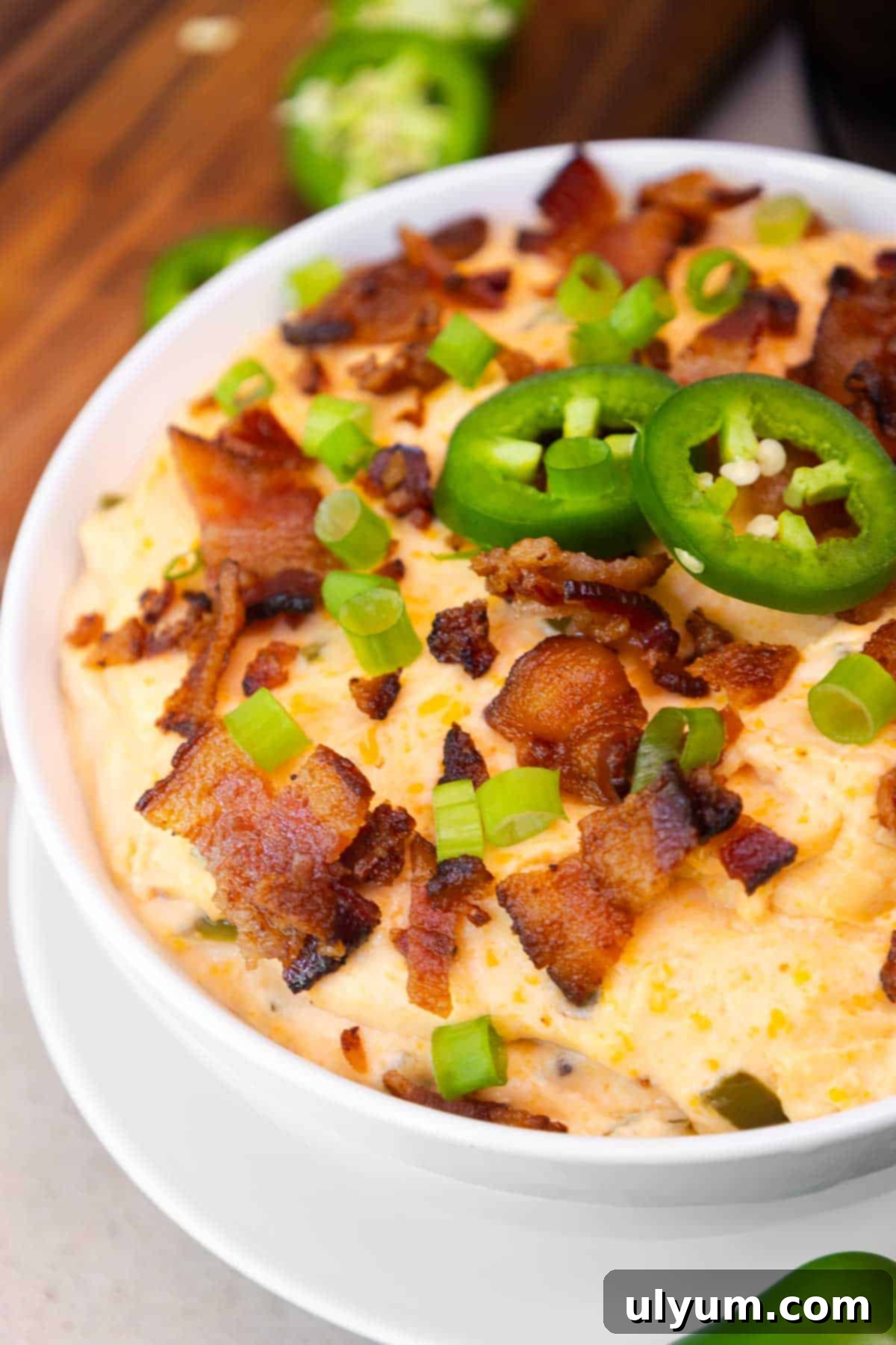Zoomed-in shot of the jalapeño popper dip showing detailed texture of melted cheese, crispy bacon pieces, and vibrant green onion and jalapeño toppings.