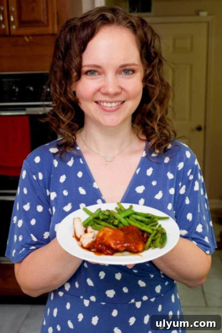 Mouthwatering Oven Baked BBQ Boneless Chicken Thighs 10 Kelsey Smith holding a plate with BBQ chicken thighs and green beans.
