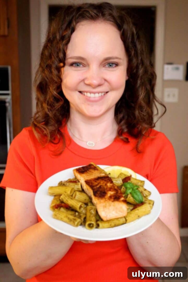 Kelsey Smith holding a plate of salmon pesto pasta.
